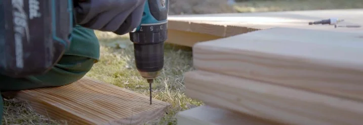 Person verschraubt Holzbretter mit Akkuschrauber